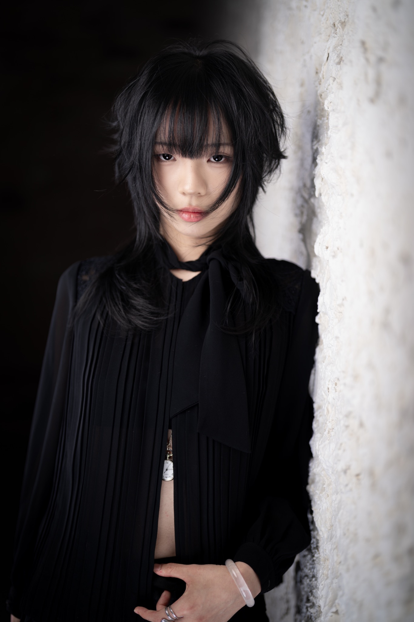 Black layered haircut portrait against a white textured wall