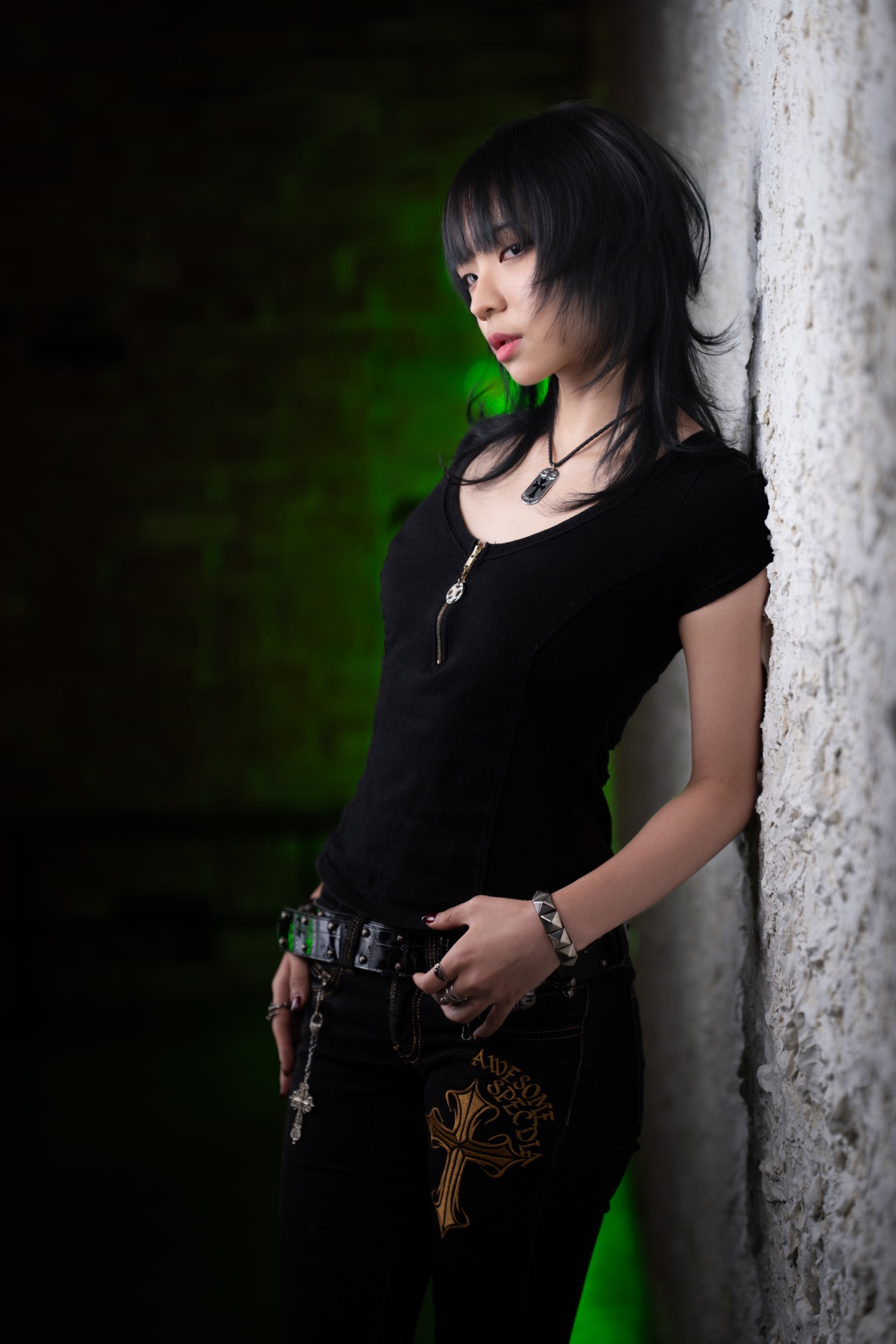 Kenn black layered wolf cut with straight fringe by a white wall